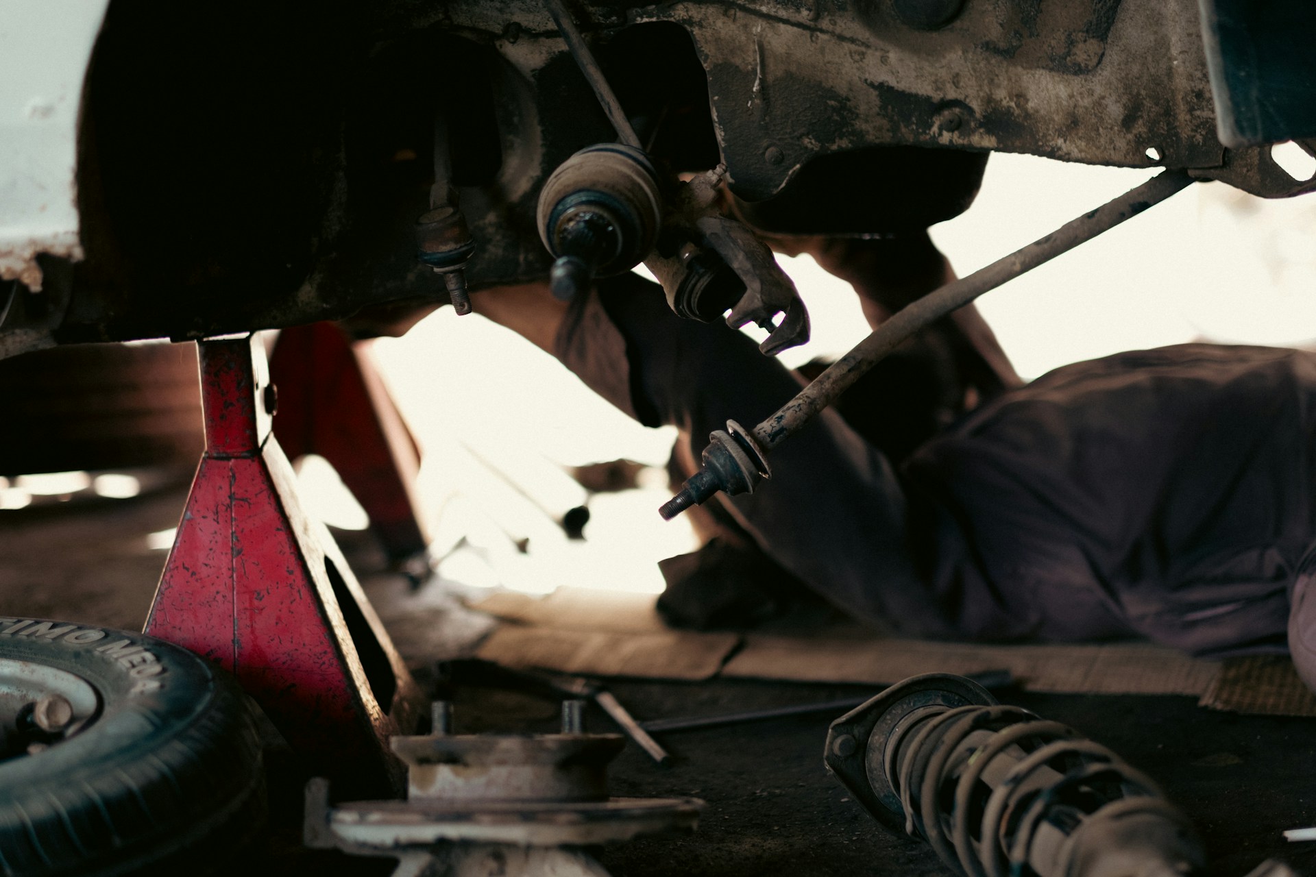tahamie-farooqui-K5624F8cipE-unsplash A man working on a car under a vehicle